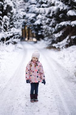 Büyük karlı ormanda sevimli küçük bir kız. Mutlu bir çocukluk. Yüksek kalite fotoğraf