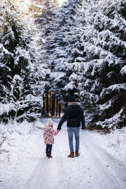 Tatlı küçük kız babasıyla karlı ormanda yürüyor. Baba ve kızı Noel tatilinde birlikte vakit geçiriyorlar. Yüksek kalite fotoğraf