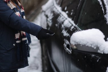 Kadın uzaktan kumandayla açık araba kullanıyor. Arabanın anahtarını tutan kadına yaklaş. Kış açık havada. Yüksek kalite fotoğraf