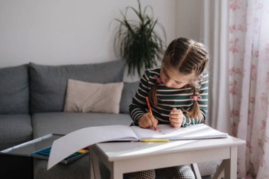 Evde çizim yapan beş yaşında bir kız. Güzel saç stili çizimi olan sevimli küçük bir kız. Yüksek kalite fotoğraf