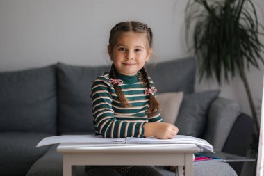 Evdeki mutlu küçük kızın portresi. Kalem kullanan güzel saç stili olan bir kız. - Evet. Yüksek kalite fotoğraf