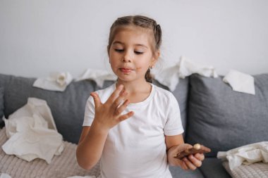 Sevimli ve güzel küçük kız çikolata yiyor ama ellerinde eriyor, o yüzden kız parmaklarını yalıyor. Yüksek kalite fotoğraf