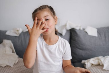 Sevimli ve güzel küçük kız çikolata yiyor ama ellerinde eriyor, o yüzden kız parmaklarını yalıyor. Yüksek kalite fotoğraf