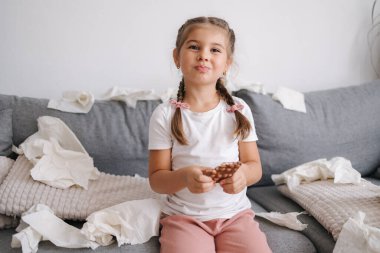 Küçük kız evde tek başına çikolata yiyor. Evdeki karmaşa ve kaos. - Evet. Yüksek kalite fotoğraf