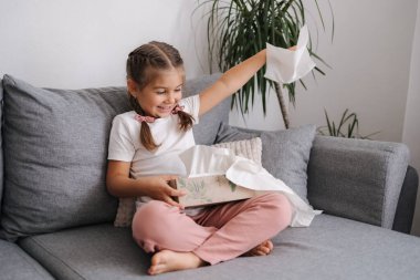 Sevimli küçük kız peçete paketini al ve eğlen. Çocuk evi darmadağın etmiş. Yüksek kalite fotoğraf