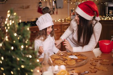 Anne ve küçük tatlı kızı Noel arifesinde mutfakta vakit geçiriyorlar. Kızlar tatil için tatlı hazırlıyor. Zencefilli çörek ve şeker. Mutlu aile.