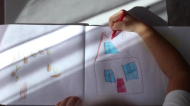 Albümde bir şeyler çizen küçük kızın en iyi görüntüsü. Tatillerde ev aktivitesi. Yüksek kalite fotoğraf