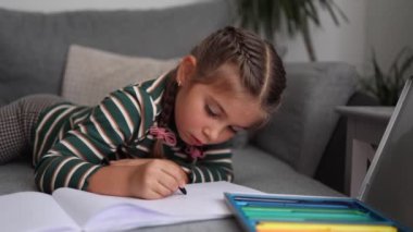Oturma odasında resim çizen sevimli küçük kız. Kız renkli kalemler kullanmış. Mutlu çocuk. Yüksek kalite fotoğraf