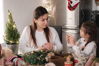 Anne ve kızı taze çam dalları ve şenlikli süslemeler kullanarak Noel çelengi yapıyorlar. Noel havası. Yüksek kalite fotoğraf