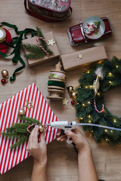 Top view of a woman using a glue gun to glue toys to a Christmas wreath. Holliday mood. High quality photo