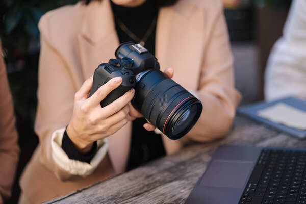 Close-up of photographer holding mirrorless camera and checking pictures. . High quality photo