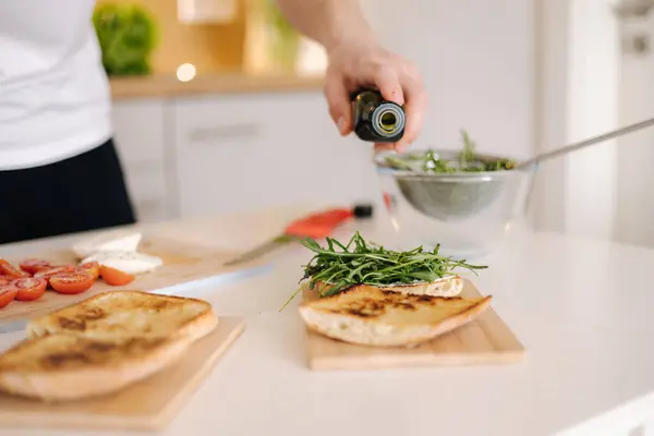 Man pouring cold pressed linseed oil on classic Italian bruschetta. Vegan healthy food. High quality photo