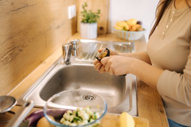 Mutfakta patates soyan bir kadının yan görüntüsü. Kadın evde vejetaryen Meksika yemeği hazırlıyor. Yüksek kalite fotoğraf