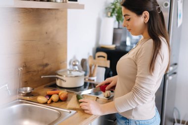 A young beautiful woman is preparing lunch in her kitchen at home. High quality photo