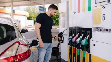 Benzin istasyonunda yakıt ikmali yapan yakışıklı genç adam. Benzin deposunda yakıt enjektörünü kullanan bir kadın var. Benzin kavramı. Yan görüş. Yüksek kalite fotoğraf