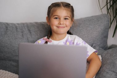 Zekice tasarlanmış küçük güzel bir kızın portresi. Beş yaşındaki kız aç ve dizüstü bilgisayar kullan. Yüksek kalite fotoğraf