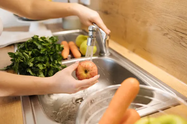 Close-up of humans hand wash apples in kitchen sink. High quality photo