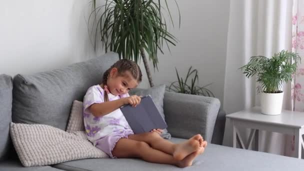 Adorável Menina Senta Casa Sofá Jogar Jogos Tablet Humor Doméstico — Vídeo de Stock