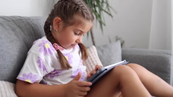 可爱的小女孩在家里用平板电脑 五岁的女孩在平板电脑上玩游戏 高质量的照片 — 图库视频影像