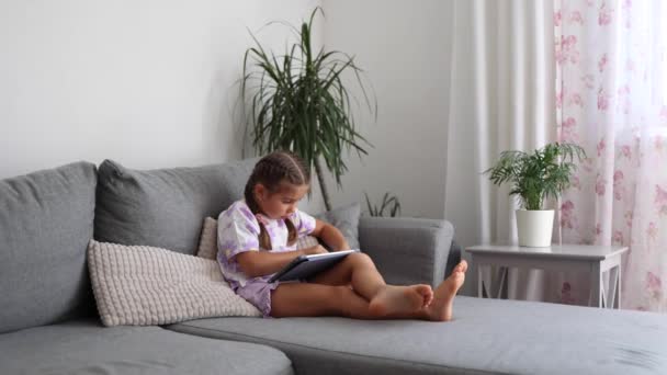 사랑스러운 소녀는 소파에 태블릿에 게임을 분위기 품질의 — 비디오
