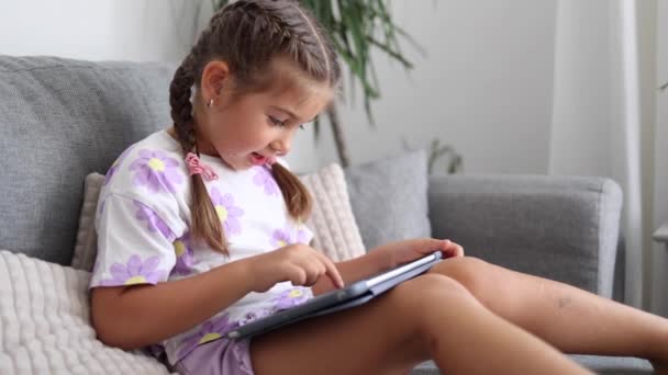 사랑스러운 소녀는 집에서 태블릿을 사용합니다 살짜리 소녀는 태블릿에서 게임을합니다 품질의 — 비디오