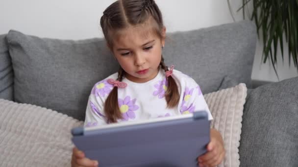 사랑스러운 소녀는 집에서 태블릿을 사용합니다 살짜리 소녀는 태블릿에서 게임을합니다 품질의 — 비디오