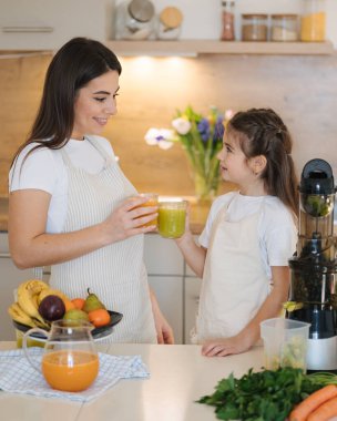 Beş yaşındaki kızıyla annesi meyve sıkacağında yapılan ev yapımı içecekleri içiyorlar. Vejetaryen içkileri. Yüksek kalite fotoğraf
