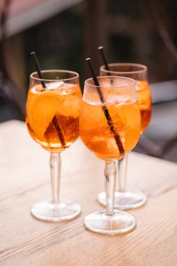 Tahta masada turuncu alkollü üç bardak. İçecekteki siyah pipet. Yüksek kalite fotoğraf