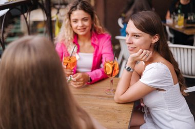 Kafede kutlama yapan üç güzel kadının yan görüntüsü. Kadınlar alkollü kokteyller içer ve eğlenir. Yüksek kalite fotoğraf