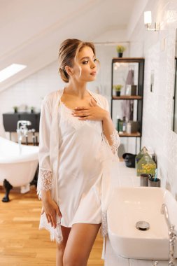 Lüks banyoda duran beyaz ipek bornozlu güzel ve narin gelin. Kadın düğüne hazırlanıyor. Yüksek kalite fotoğraf