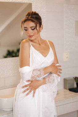 Lüks banyoda duran beyaz ipek bornozlu güzel ve narin gelin. Kadın düğüne hazırlanıyor. Yüksek kalite fotoğraf