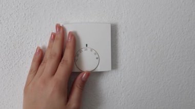 İnsan eli evdeki ısıtıcıyı kapatır. Merkezi ısıtma termostatı kontrol ayarları. Mesaj için yer. Kadın tasarruf etmek için termostatı geri çeviriyor. Yüksek kalite 4k görüntü