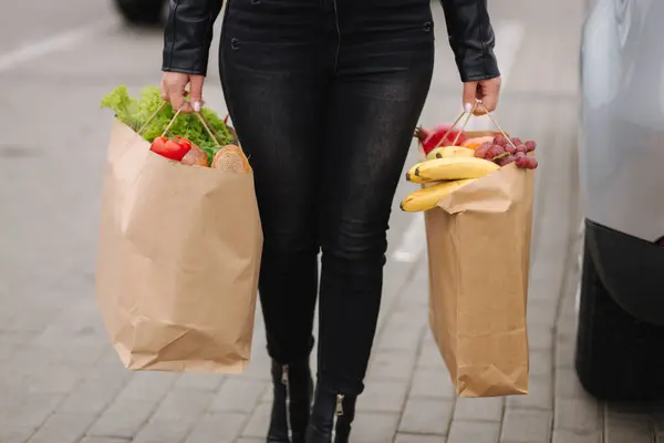 Groceries from a supermarket in a eco craft package. Food delivery concept. Paper eco bags full of fresh food. Woman hold two package. High quality photo