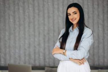 Masanın önünde dizüstü bilgisayarla duran açık mavi gömlekli güzel kadın ofis çalışanı portresi. İş yeri. Yüksek kalite fotoğraf