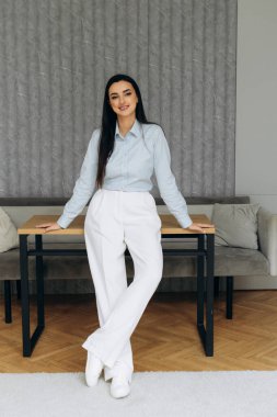 Resmi tarzda çekici bir kadın avukat ofis masasının önünde duruyor. İş sırasında iş kadınının portresi. Yüksek kalite fotoğraf