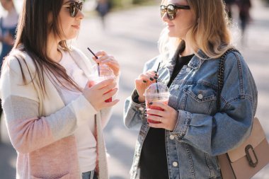 İki bayan arkadaş ahududulu limonata içip konuşuyorlar. Mutlu kadın dışarıda yürüyor..