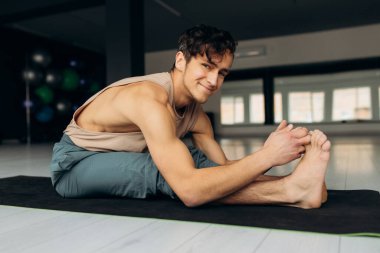 Vücudunu esneten mutlu atletik genç adam. Yoga antrenmanından hoşlanan adam, yan görüş. Sağlıklı yaşam tarzı kavramı. Yüksek kalite fotoğraf