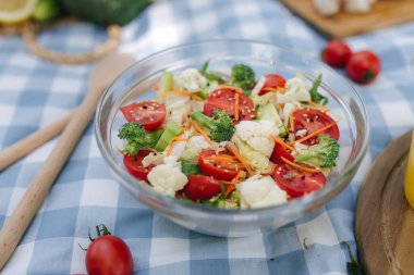Açık havada taze vejetaryen salatası ve mavi peçete. Dışarıda vejetaryen yemeği konsepti. Yüksek kalite fotoğraf