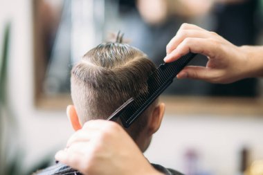 Küçük çocuk saç kesimi tarafından Kuaför Berber Dükkanı, sandalyede otururken Başlarken