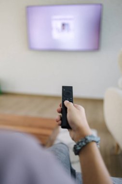 Çocuğun yakın çekim görüntüsü televizyonun sağ elinde uzaktan kumandayı tutuyor. Yüksek kalite fotoğraf