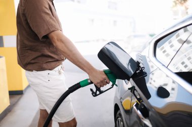 Benzin istasyonunda yakıt ikmali yapan yakışıklı genç adam. Benzin kavramı. Yan görüş. Orta seçim. Yüksek kalite fotoğraf