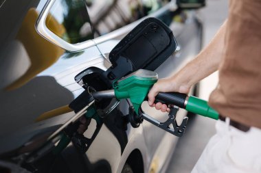 Benzin istasyonunda bir arabaya yakıt ikmali yapan adama yakın çekim. İnsan eliyle yapılan orta seçim yeşil yakıt pompasını tutuyor. Benzin. Yüksek kalite fotoğraf