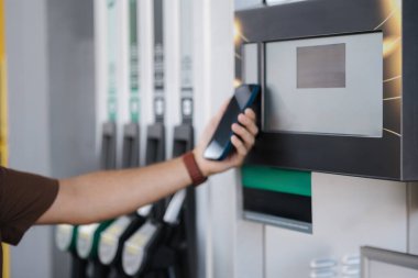 Benzin istasyonunun parasını akıllı telefonuyla ödeyen bir adam. Temassız ödeme. Yüksek kalite fotoğraf