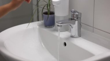 Musluk ve akan su. Krom malzemeden yapılmış su musluğu. Çocuk suyu kapatıyor. Yüksek kalite 4k görüntü