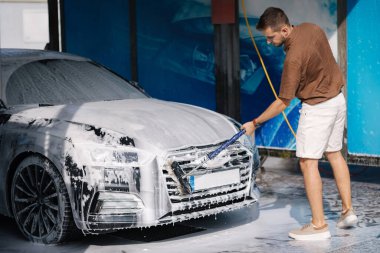 Adam araba yıkamada özel bir fırçayla araba yıkıyor.