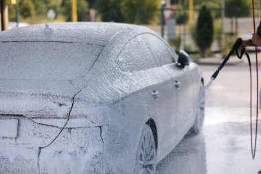 Aktif köpük kullanarak araba temizleme. Yakışıklı adam lüks arabasını oto yıkamayla yıkıyor. Yüksek kalite fotoğraf