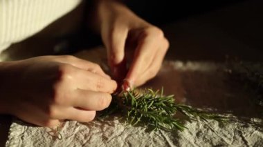 Kadın eli biberiye filizi bağlamak için doğal sicim kullanır. Kurutma ve baharat kullanımı için taze otlar hazırlanıyor. Yüksek kalite 4k görüntü