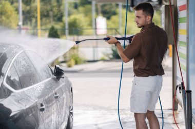 Yakışıklı bir adam lüks arabasını self-servis araba yıkamada yıkıyor. Yüksek kalite fotoğraf