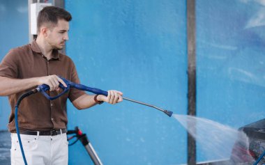 Araba yıkama. Adam parlamak için yüksek basınçlı ağda kullanıyor. Son işlem. Yüksek kalite fotoğraf