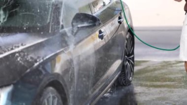 Yakışıklı bir adam lüks arabasını self-servis araba yıkamada yıkıyor. Yüksek kalite 4k görüntü